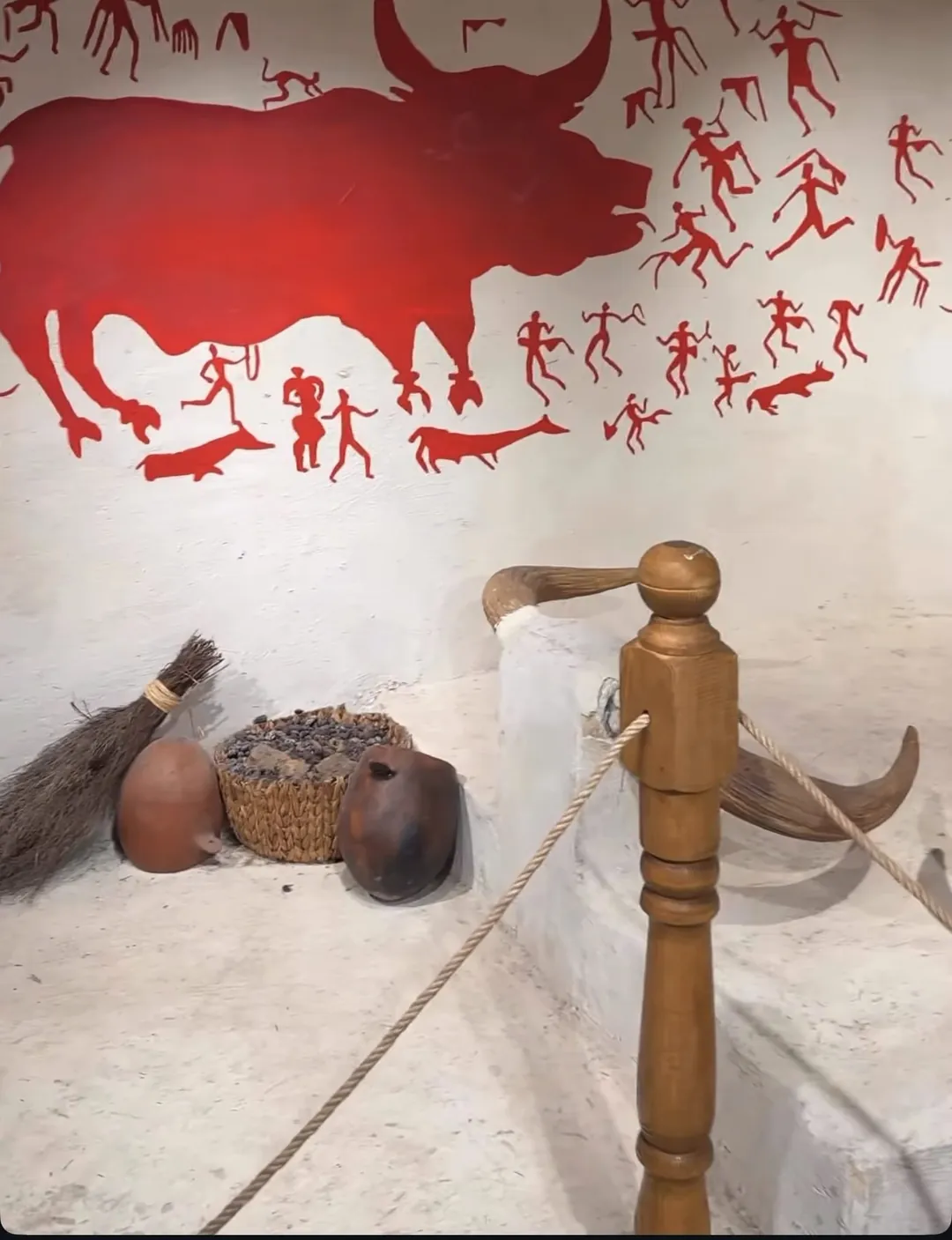 Çatalhöyük ev canlandırmasında kırmızı boğa ve av sahnesini gösteren duvar resmi, sekiler ve boğa boynuzları